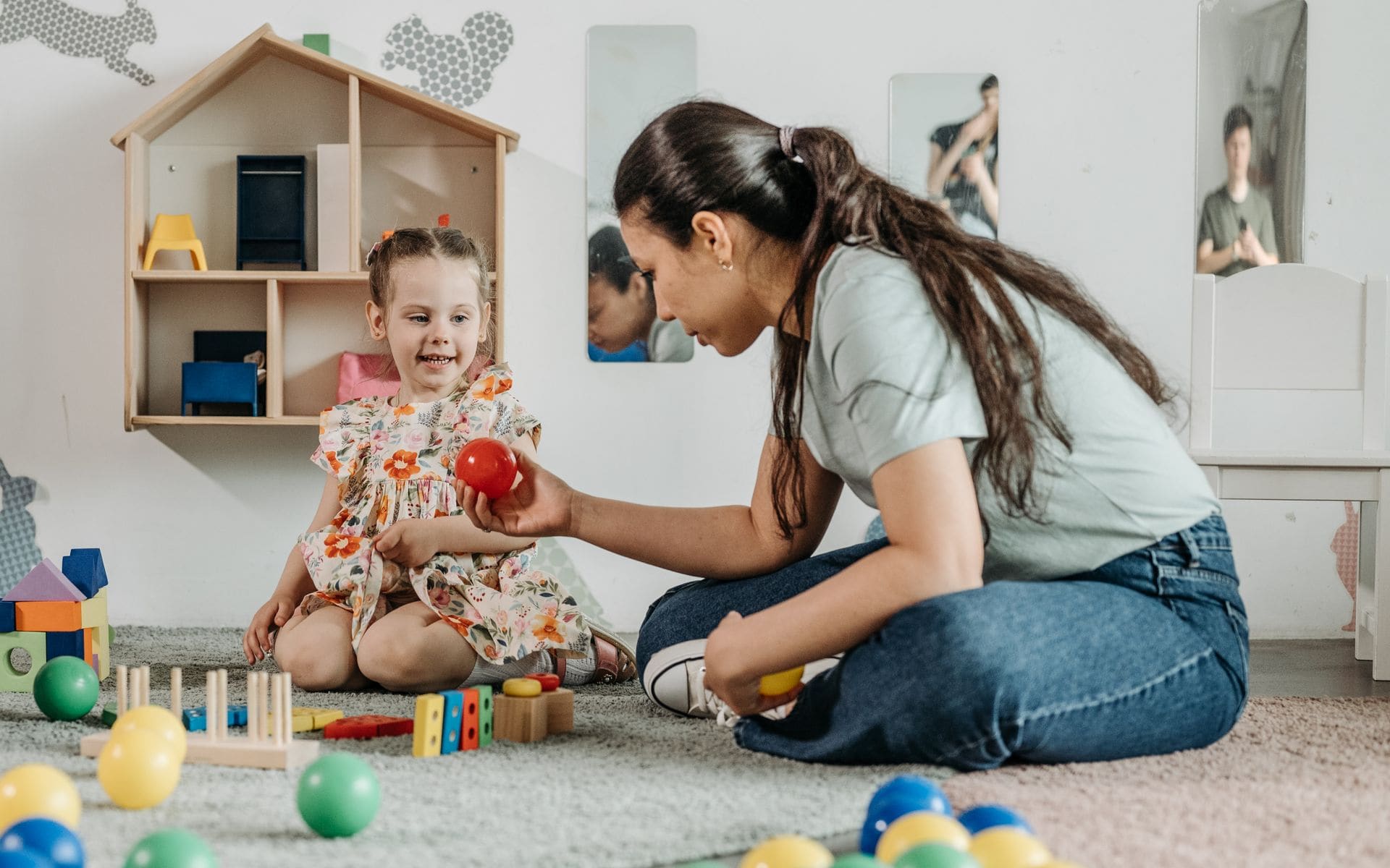 Educator playing with a young girl in a warm, home-based care setting